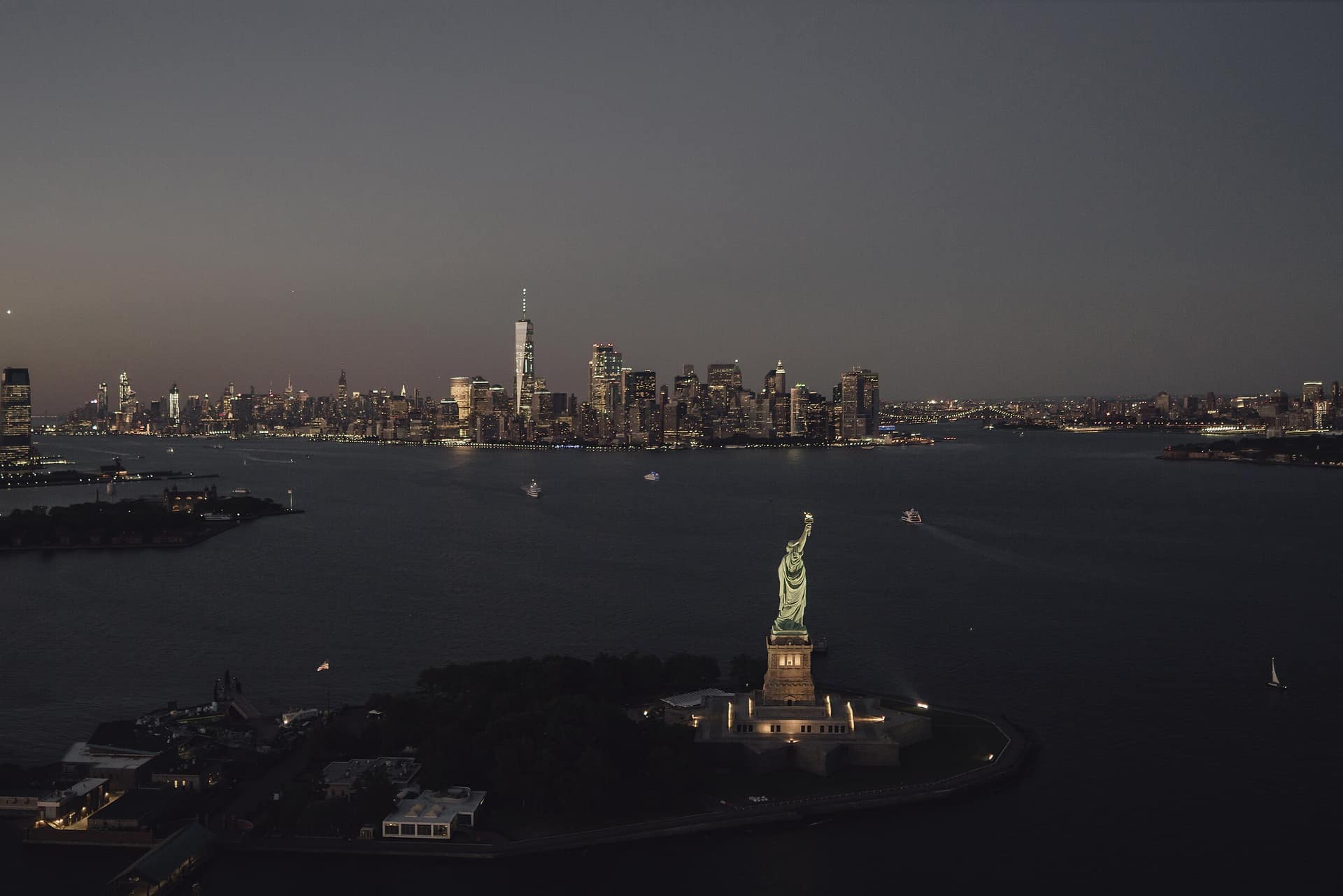 Aerial view of the Statue of Liberty and Manhattan skyline at dusk